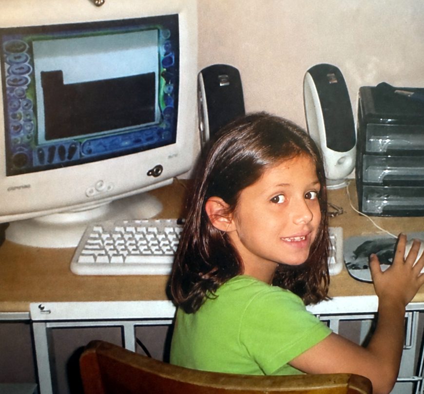 Karleigh as a child at a Compaq computer, turning to look at the camera.