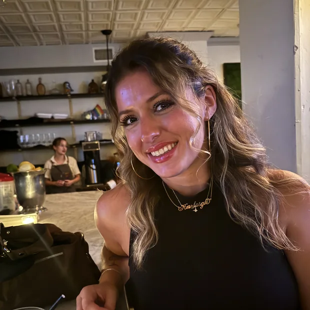 Karleigh at a bar, laughing, holding a drink.