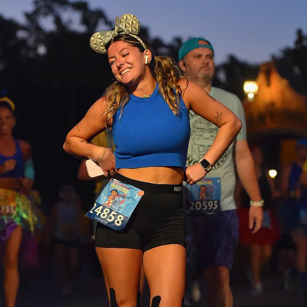 Karleigh running a runDisney race at dusk in Epcot ears and a race bib.